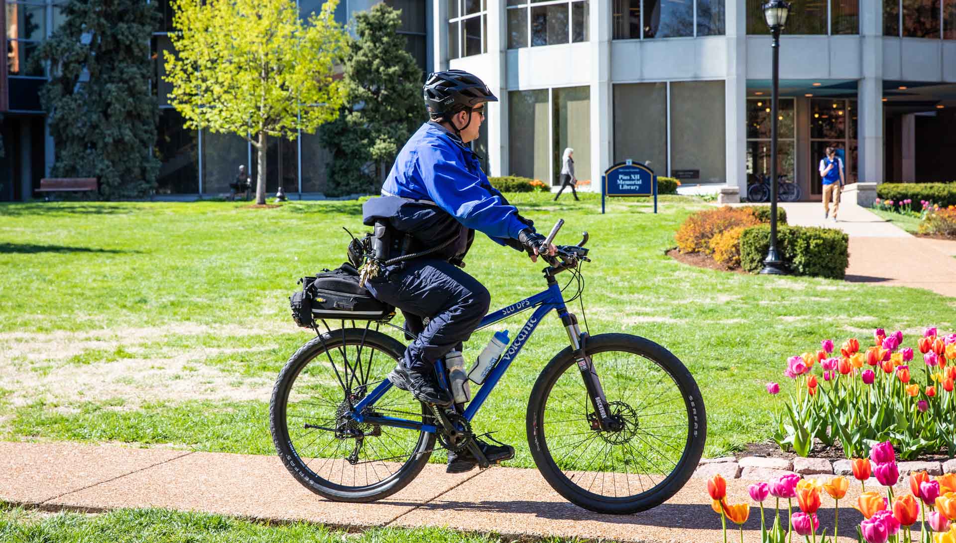 A public safety officer rides a bicycle on campus