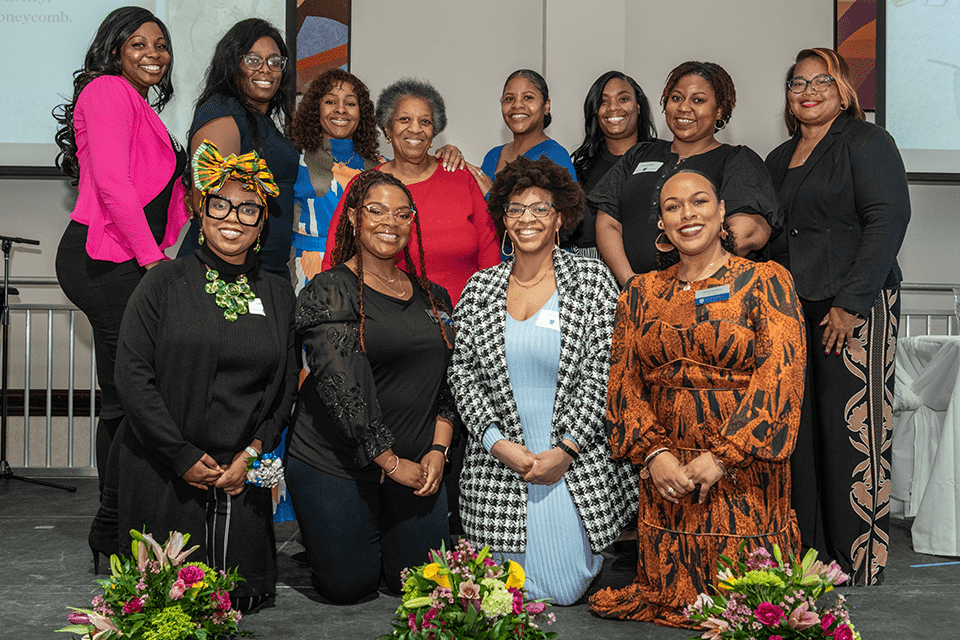 BAA Prayer Breakfast A group of 12 women pose for a photo on a stage.
