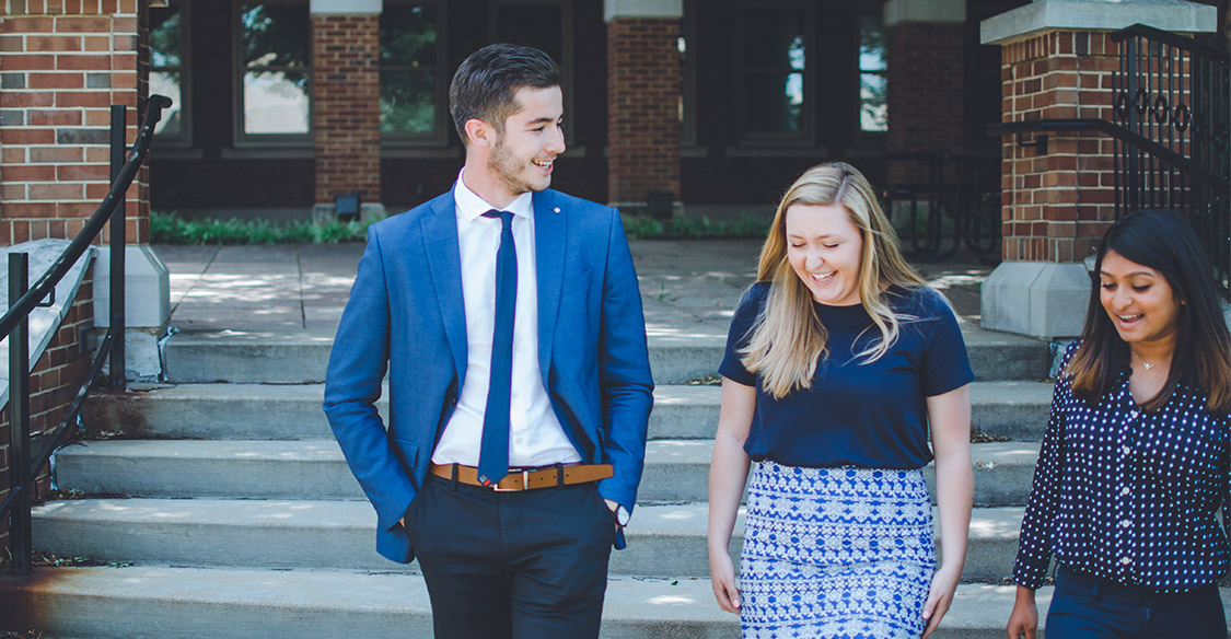 three MBA students walking outside on stairs