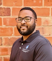 Michael Hankins Michael Hankins, headshot, wears a SLU polo shirt and smiles, standing in front of a brick wall.