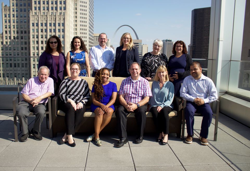 A group of health law faculty and staff sit together on the roof top of Scott Hall Health Law Faculty and Staff