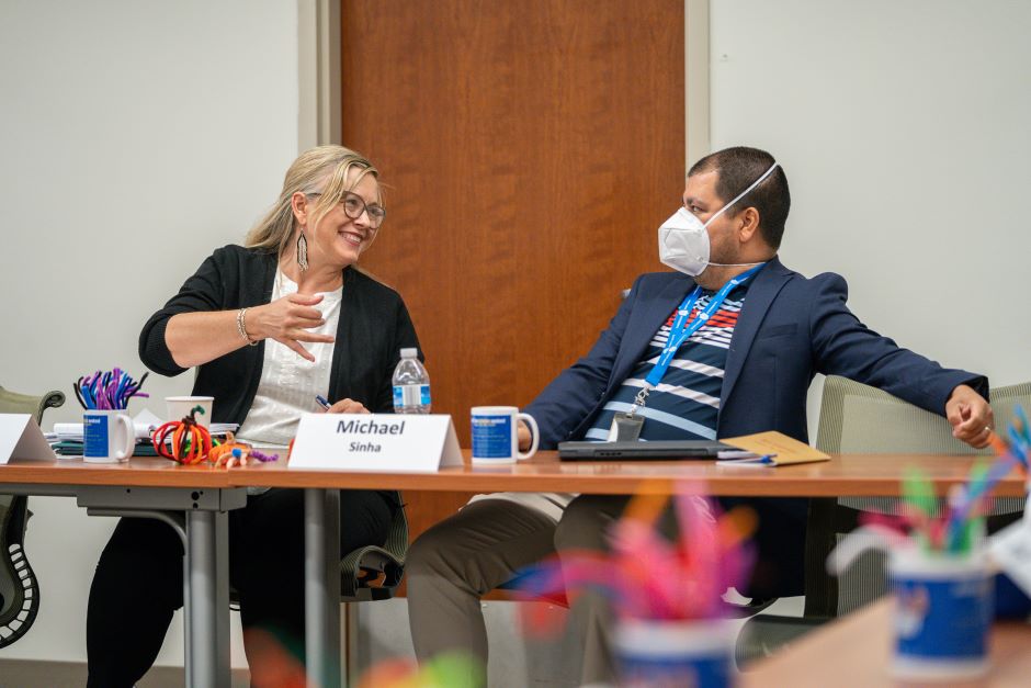 Profs. Michael Sinha and Kelly Gillespie speak to each other Profs. Sinha and Gillespie speak at a table at the Health Law Scholars Weekend