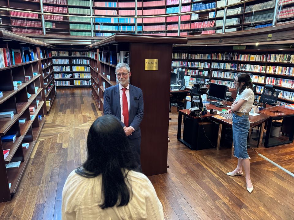 students and tour guide in a library surrounded by shelves of books and tables