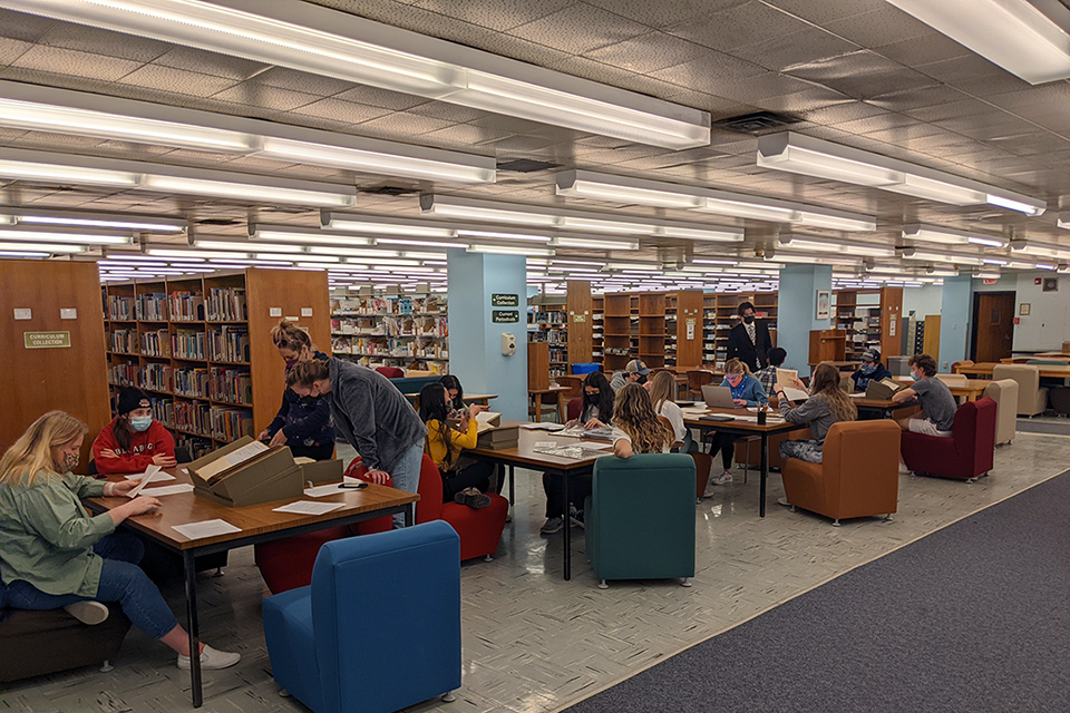 Archives Intruction Students examine books while sitting at tables in a library.