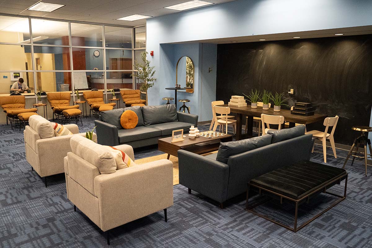 SGA WellSPACE A room with sofas, tables and chairs, padded arm chairs and lounge seats with footrests.