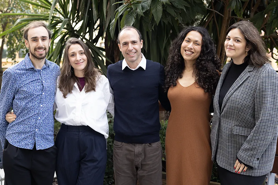 The members of SLU-Madrid counseling team pose for a group photo in front of several plants.