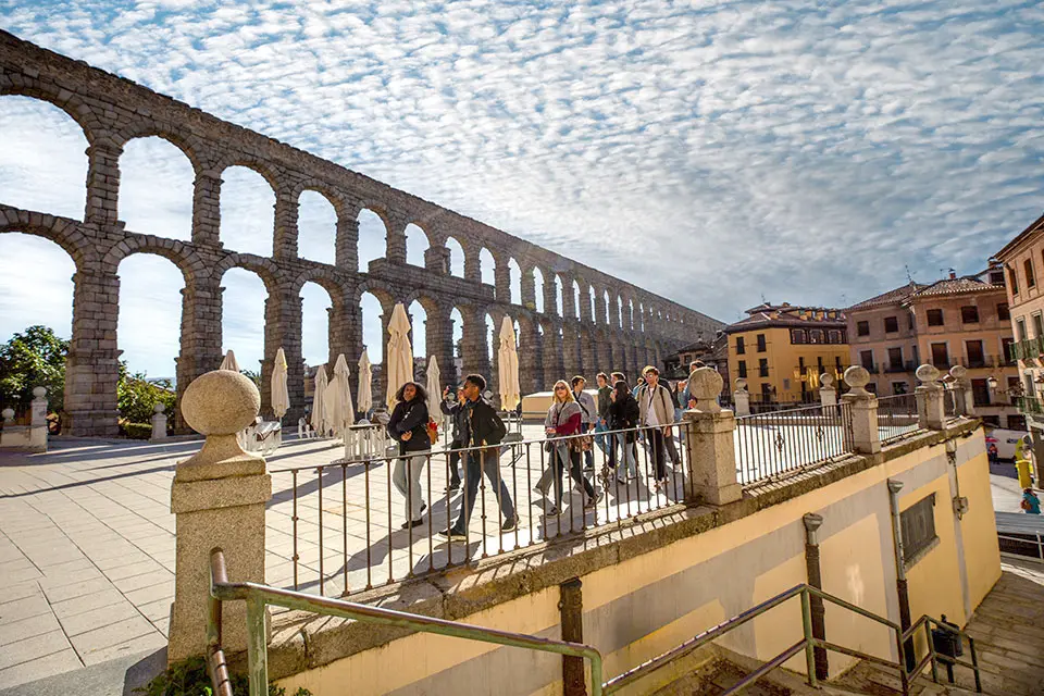 Segovia A Roman aqueduct with arches made of granite brick stretches itself next to a town.