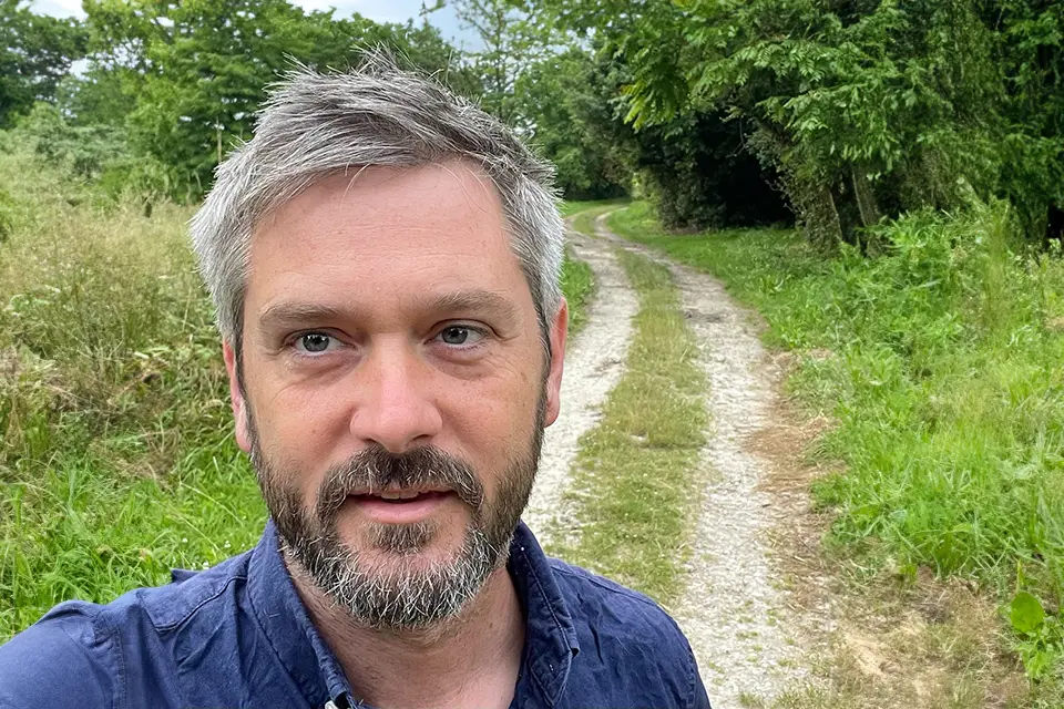 Timothy Ryan Day, Ph.D. A man looking directly at the camera for a photo with a country road behind him.