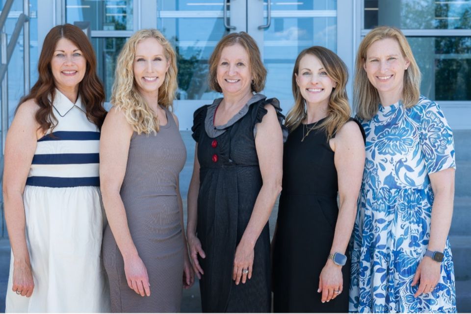 Five faculty members of the dermatopathology program stand in front of a building