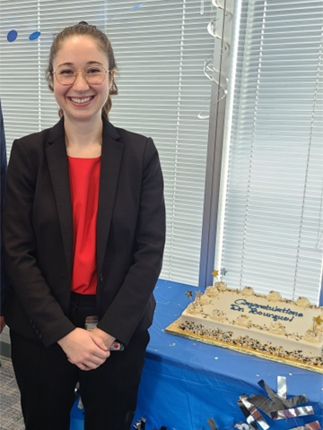Headshot of Jess Borque, smiling at the camera, wearing a red shirt and black blazer. Headshot of Jess Borque