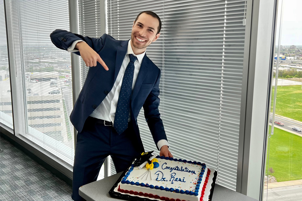 valerio-rossi-defense Valerio Rossi celebrating, holding a sheet cake with the words "Congratulations Valerio" iced on the top of the cake