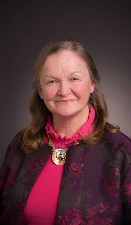 a woman in a pink shirt poses for a picture