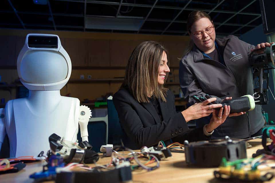 SLU researchers examine robotics pieces in a lab.