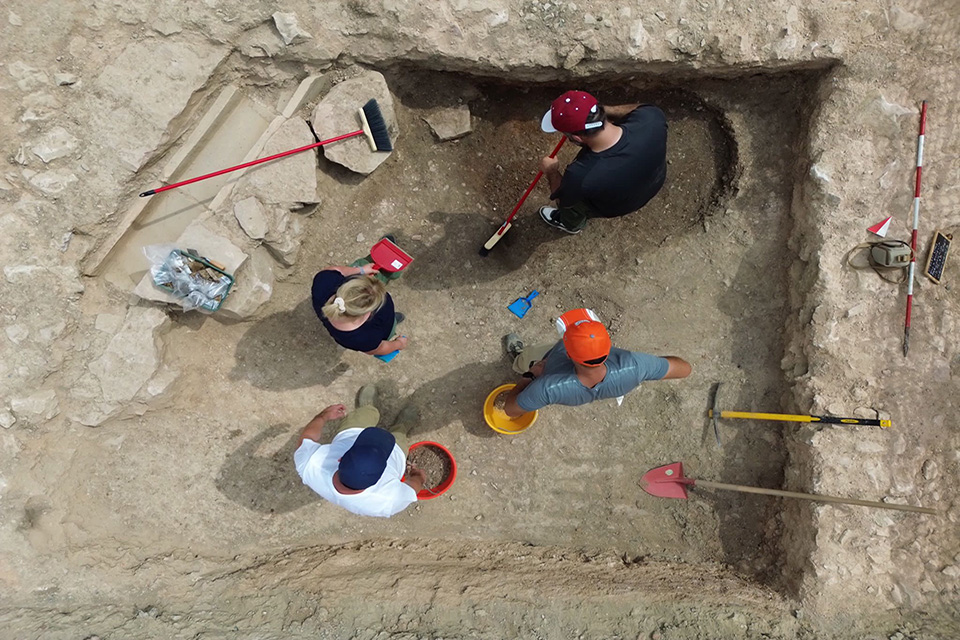 The team, seen from above, works at the site with shovels, buckets and brooms.